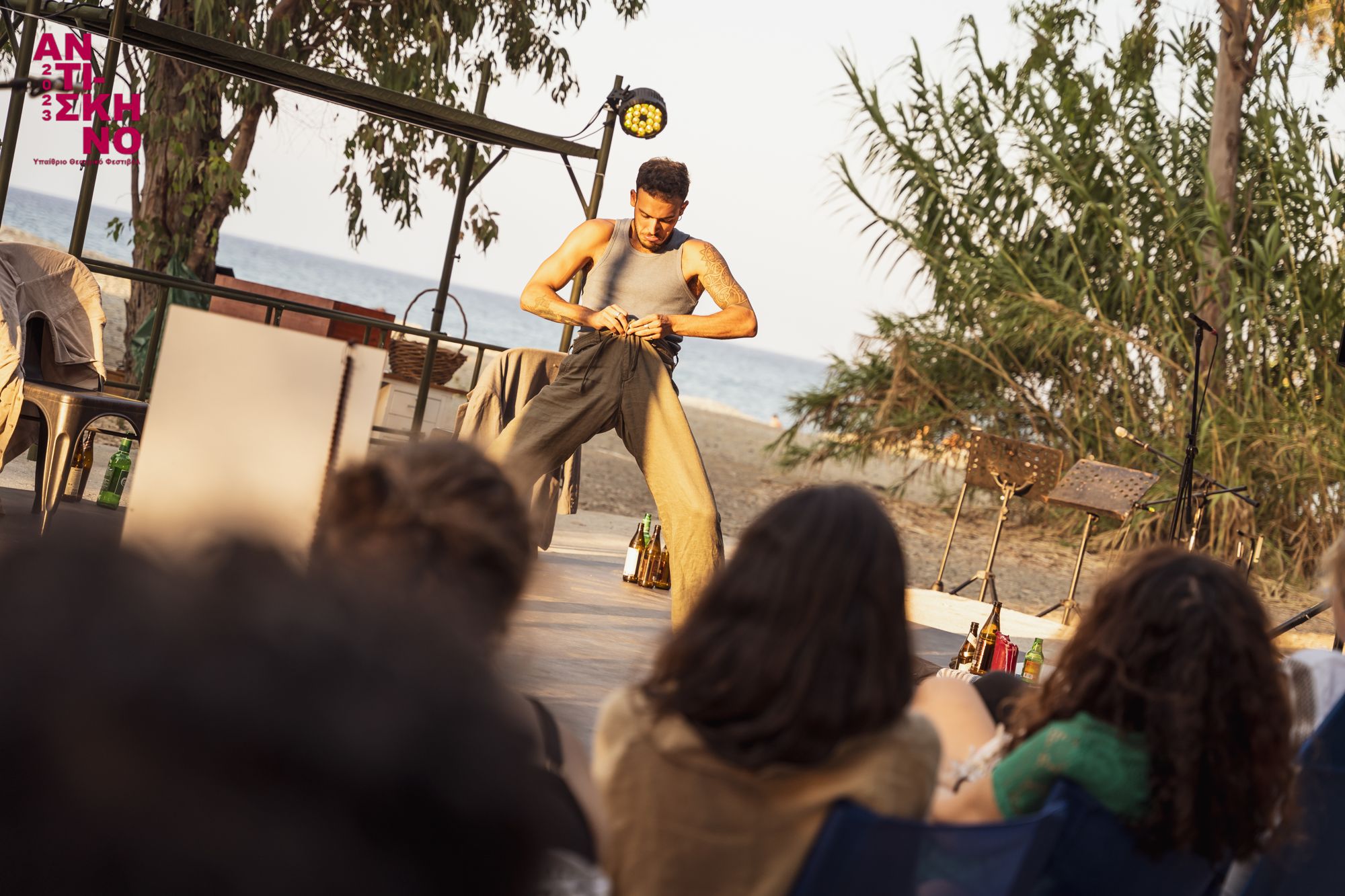 Alexandros performing on an outdoor stage by the sea, audience in the foreground