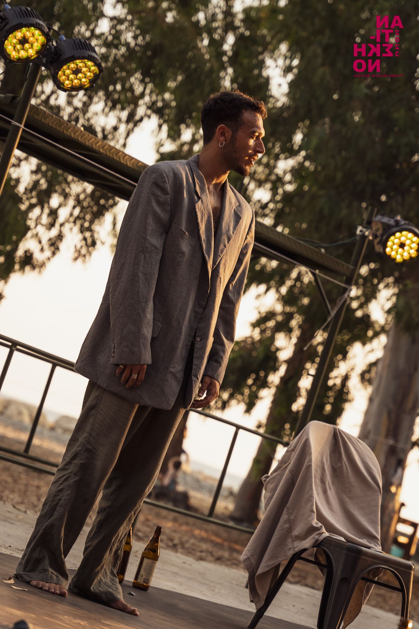 Alexandros standing in an oversized grey suit, looking to the side