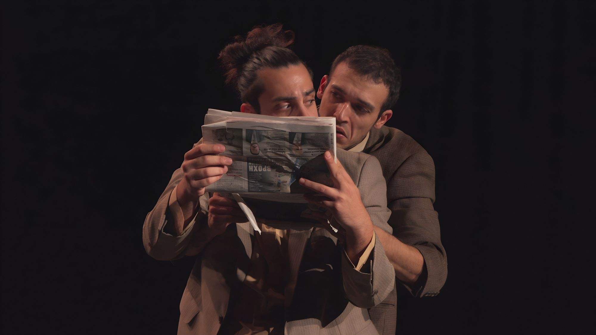 The two performers in brown suits huddled behind one newspaper
