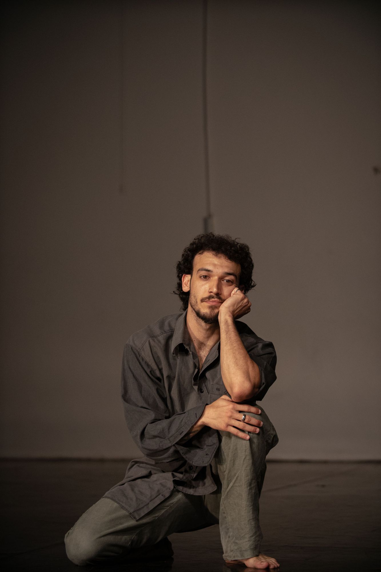 Alexandros kneeling on one knee, chin resting on his hand