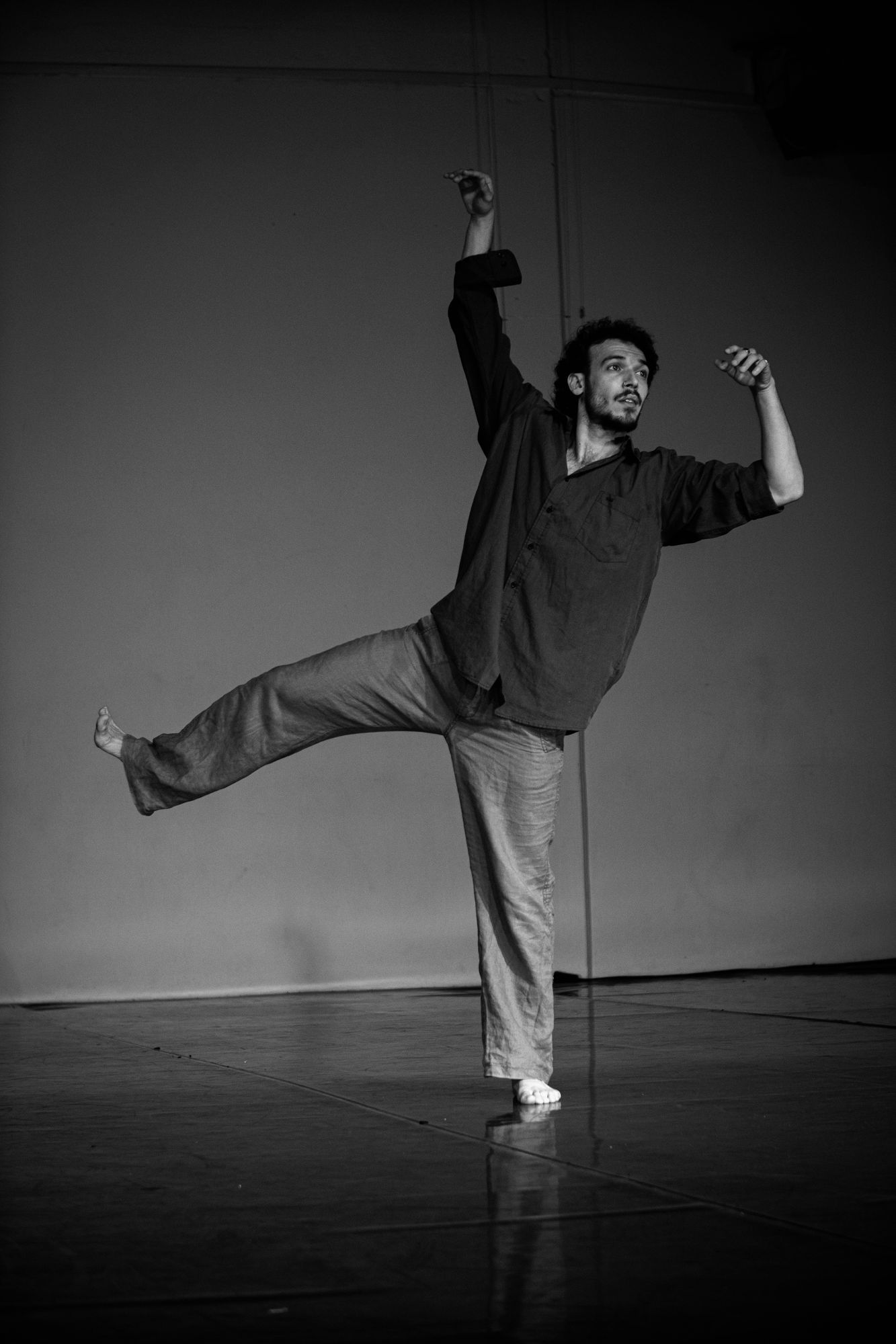 Alexandros balancing on one leg, arms raised, in a studio